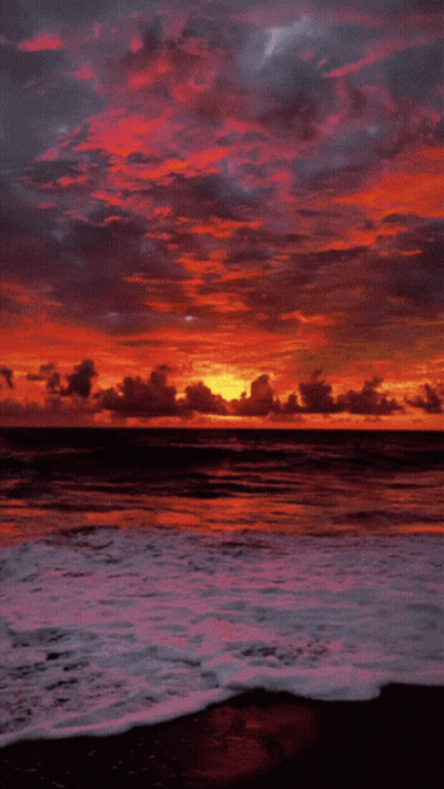 A Sunset Over A Body Of Water With A Few Clouds GIF