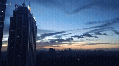 A Sunset Over A City With A Skyscraper In The Foreground That Says ' Jakarta ' On It GIF