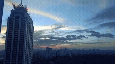 A Sunset Over A City With A Skyscraper In The Foreground That Says Shark GIF