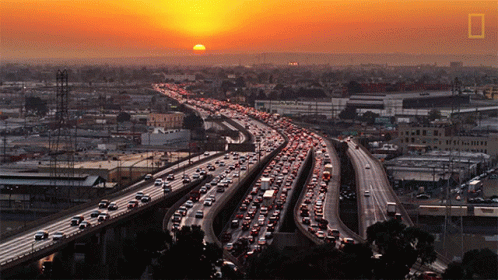 A Sunset Over A Highway With A Lot Of Cars On It GIF