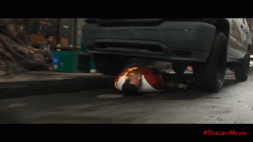 A Superhero Is Laying On The Ground With A #Shazammovie Written On The Bottom GIF