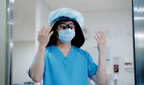A Surgeon Wearing A Mask And Goggles Stands In Front Of A Sign That Says ' Surgery ' GIF