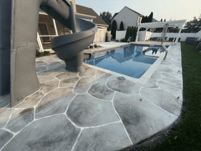A Swimming Pool With A Slide And A Concrete Patio GIF