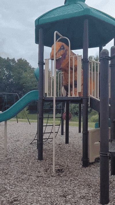 A T-Rex Costume Is On A Playground Set GIF