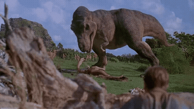 A T-Rex Is Eating A Dead Animal In The Grass GIF
