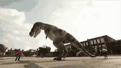 A T-Rex Is Playing Basketball With A Group Of Kids In Front Of A School . GIF