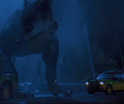 A T-Rex Is Standing In Front Of A Car That Says ' Jurassic Park ' On The Side GIF