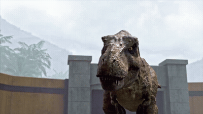 A T-Rex Is Standing In Front Of A Stone Wall GIF