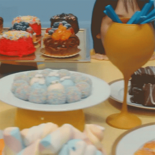 A Table Topped With Plates Of Food Including A Cake GIF