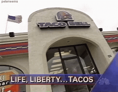 A Taco Bell Restaurant With A Banner That Says " Life Liberty Tacos " GIF