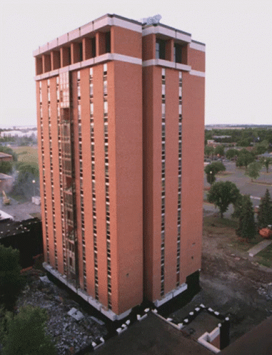 A Tall Brick Building With A Satellite Dish On Top GIF