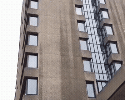 A Tall Building With Lots Of Windows And A White Sky In The Background GIF