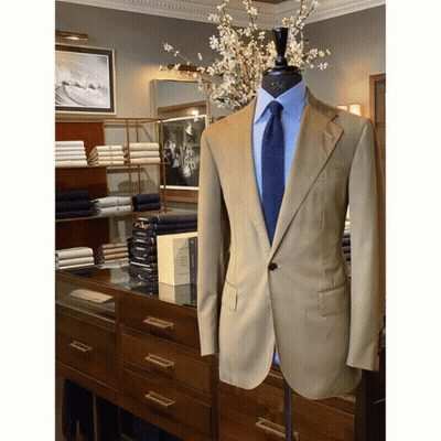 A Tan Suit With A Blue Tie Is On Display In A Store GIF