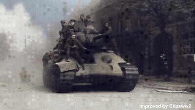 A Tank With The Number 7 On The Side Is Driving Down A Street GIF
