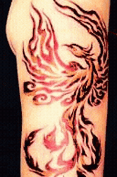 A Tattoo Of A Phoenix On A Person 'S Arm . GIF