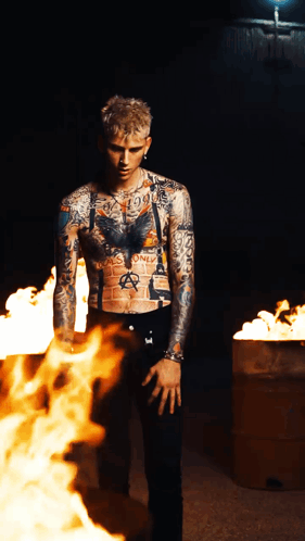 A Tattooed Man Stands In Front Of A Fire That Says Anarchy On His Chest GIF
