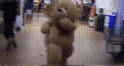 A Teddy Bear Is Dancing In A Store While A Man Looks On . GIF