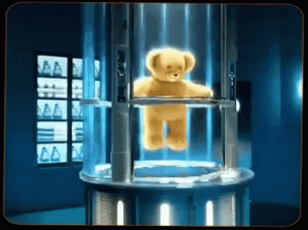 A Teddy Bear Is Floating In A Clear Container GIF