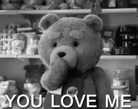 A Teddy Bear Is Holding A Sign That Says `` You Love Me '' In A Black And White Photo . GIF
