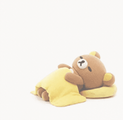 A Teddy Bear Is Laying On A Yellow Blanket Next To A Pillow . GIF