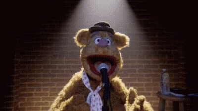 A Teddy Bear Is Singing Into A Microphone While Wearing A Tie . GIF