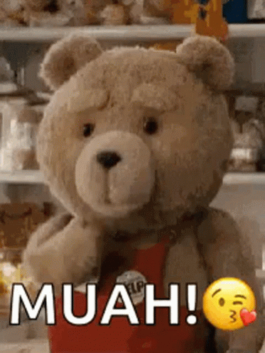 A Teddy Bear Is Standing In Front Of A Shelf With A Smiley Face And The Words Muah ! GIF