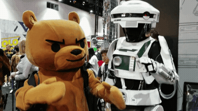 A Teddy Bear Is Standing Next To A Robot Costume GIF