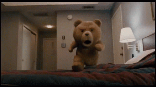 A Teddy Bear Is Standing On A Bed With The Number 8 On The Wall GIF