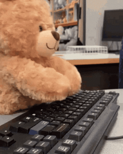 A Teddy Bear Is Typing On A Black Keyboard With The Esc Key Visible GIF