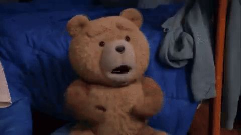 A Teddy Bear Is Walking On A Carpet In A Dark Room . GIF