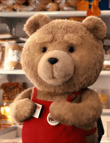 A Teddy Bear Wearing A Red Apron With A Badge That Says " Help " GIF