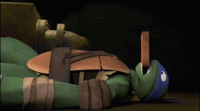 A Teenage Mutant Ninja Turtle Is Laying On The Floor GIF