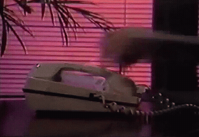 A Telephone Is On A Table In Front Of A Window With Blinds . GIF