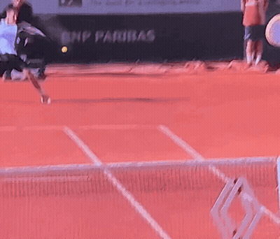 A Tennis Ball Is Being Thrown In The Air On A Red Court GIF