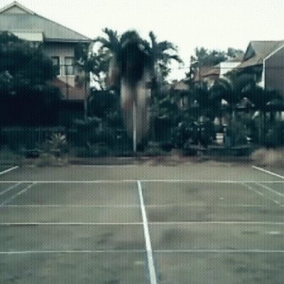 A Tennis Court With Palm Trees In The Background And Houses In The Background GIF
