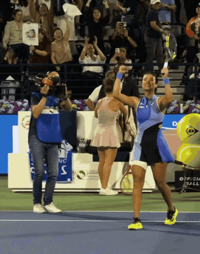 A Tennis Player Holds Her Racket In The Air In Front Of A Crowd GIF