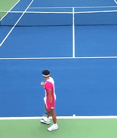 A Tennis Player In A Pink And White Outfit Is Swinging A Racket GIF
