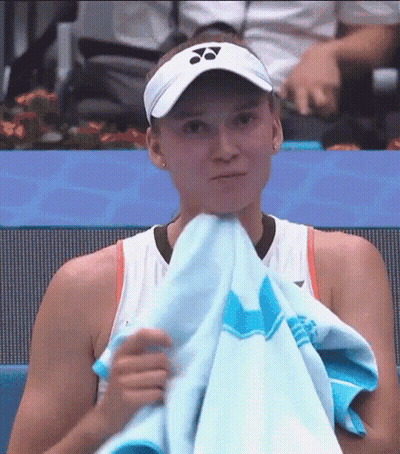A Tennis Player Is Covering Her Face With A Towel While Wearing A Visor . GIF