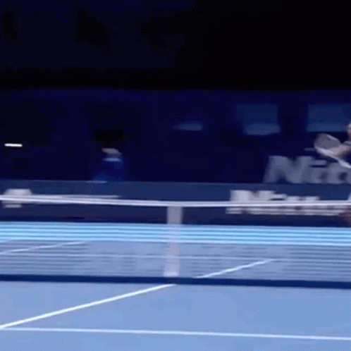 A Tennis Player Is Hitting A Ball On A Blue Court GIF
