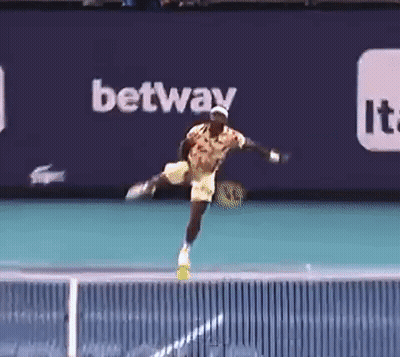 A Tennis Player Is Jumping In The Air While Holding A Tennis Racquet . GIF