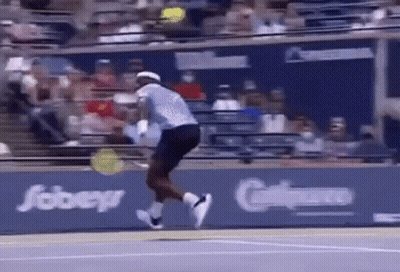 A Tennis Player Is Jumping In The Air While Holding A Tennis Racquet . GIF