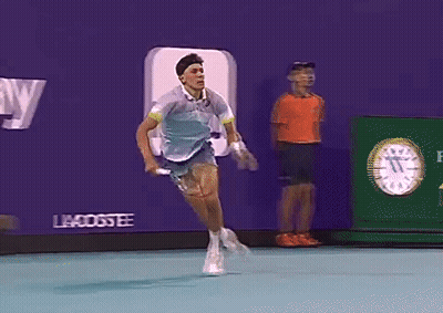 A Tennis Player Is Running On A Court In Front Of An Advertisement For Betty GIF