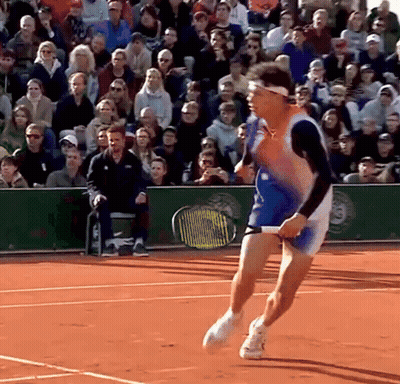 A Tennis Player Is Running On A Court With A Crowd Behind Him GIF