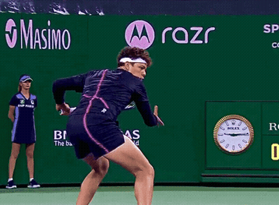 A Tennis Player Is Swinging A Racket In Front Of A Rolex Clock GIF