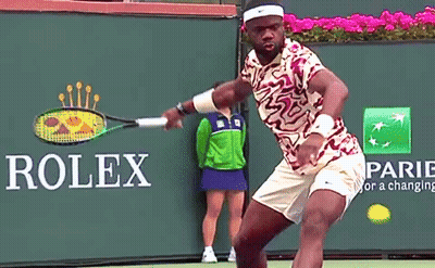 A Tennis Player Is Swinging A Racket In Front Of A Rolex Sign GIF