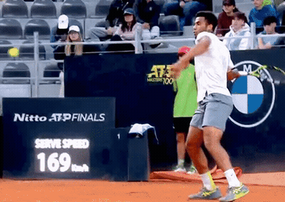 A Tennis Player Is Swinging A Racket In Front Of A Sign That Says Nitto Atp Finals GIF