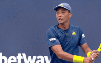 A Tennis Player Is Swinging A Racket In Front Of A Tau Sign GIF