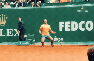 A Tennis Player Stands In Front Of A Green Wall That Says Fedco GIF