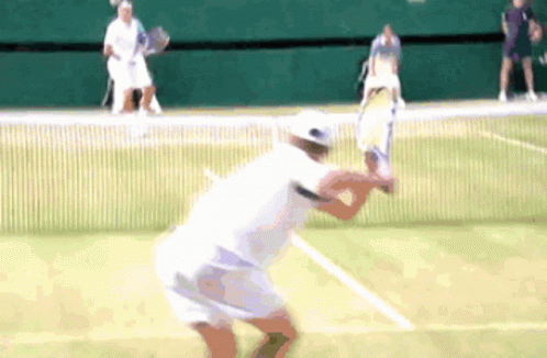 A Tennis Player Swings A Racket At A Tennis Ball GIF