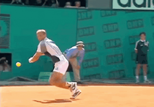 A Tennis Player Throws A Tennis Ball On A Court With An Ad For Adidas In The Background GIF